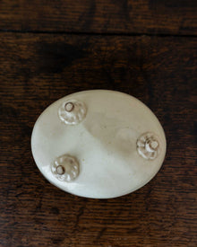 White ceramic mould with four small feet on a wooden surface