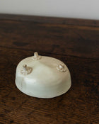 White ceramic mould with decorative feet on a wooden surface