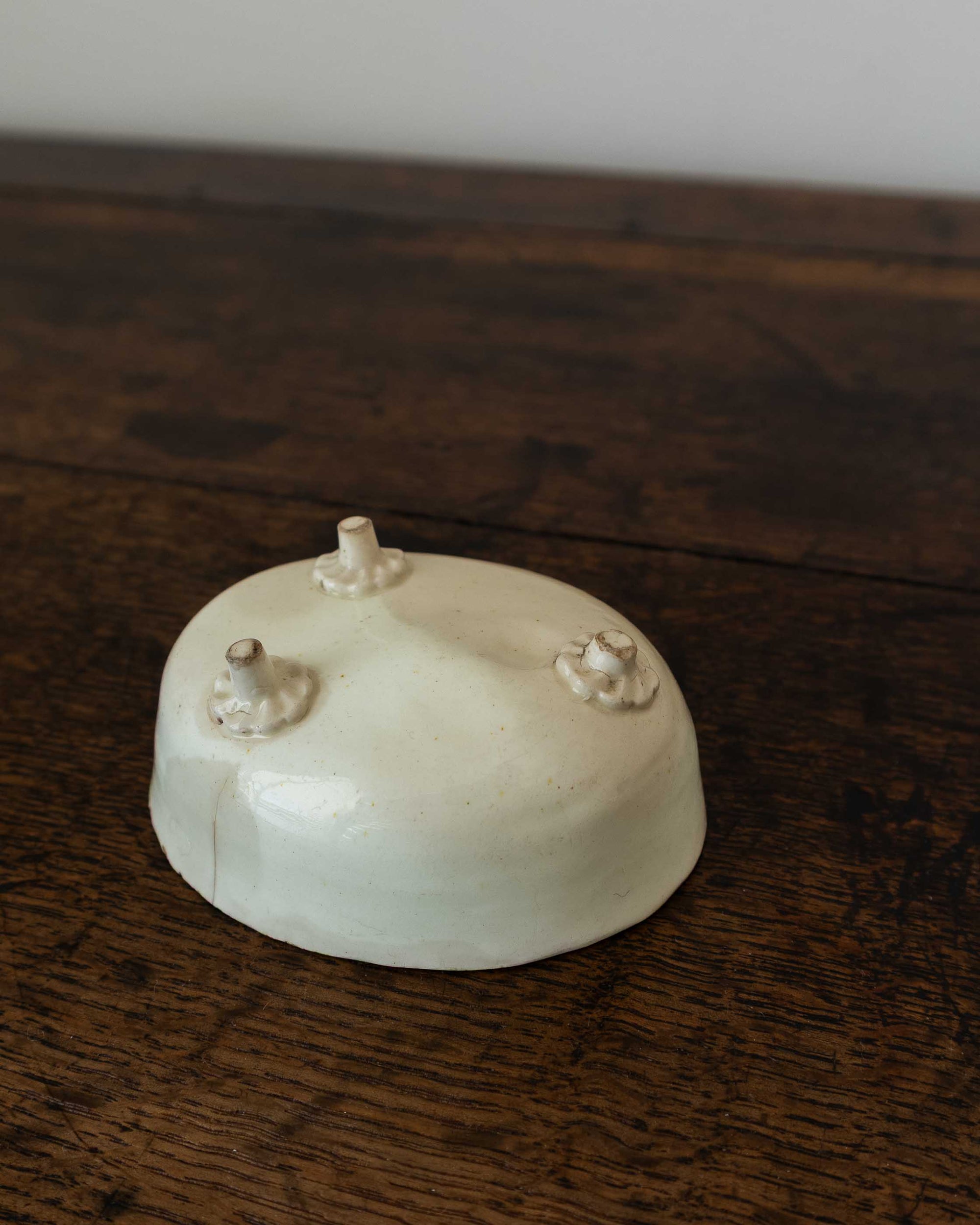 White ceramic mould with decorative feet on a wooden surface