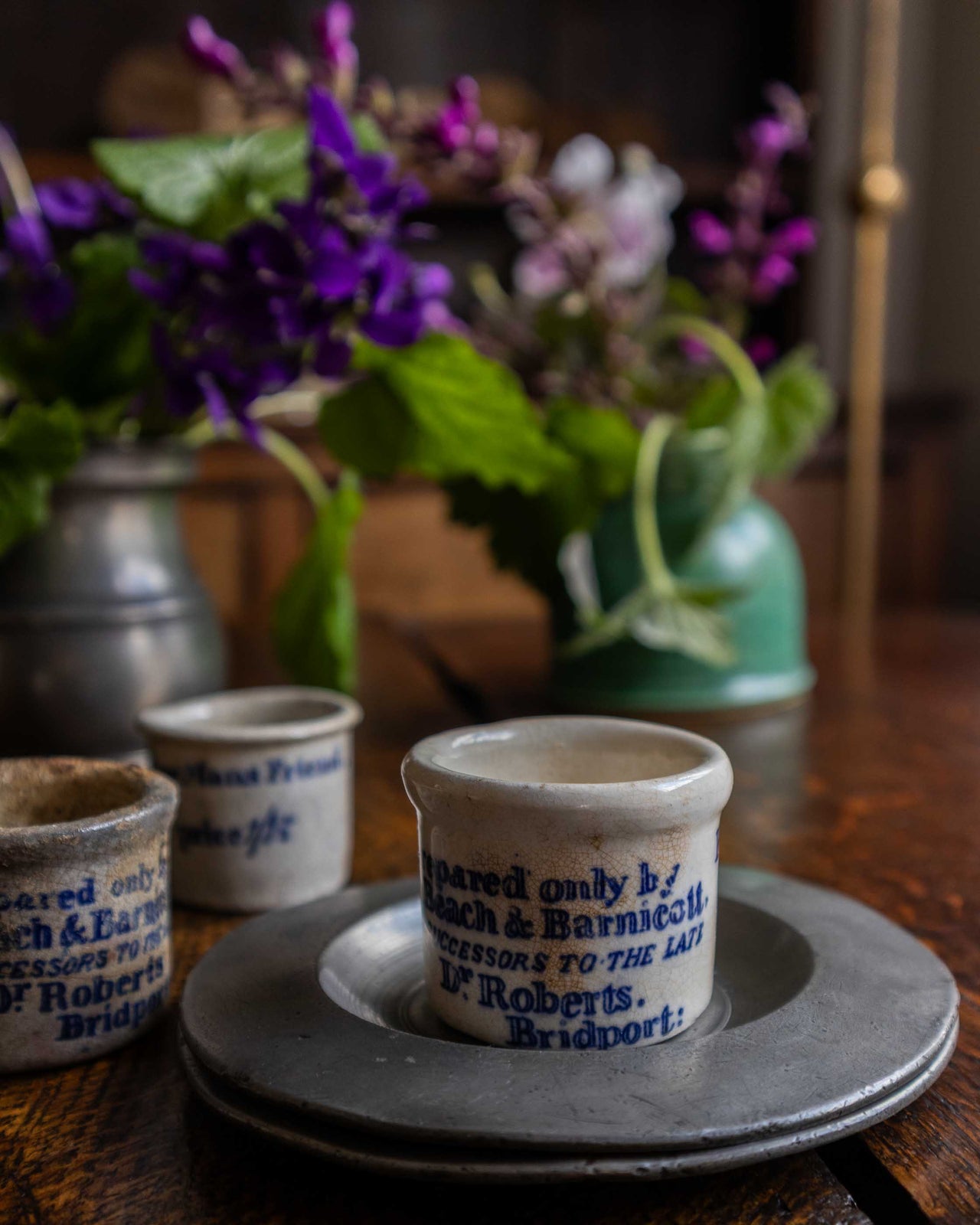 Ceramic pots with text on a wooden table with flowers in the background