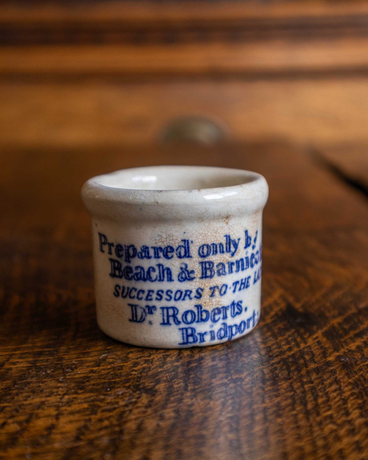 Small ceramic pot with blue text on a wooden surface