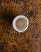 Small white ceramic pot on a wooden surface