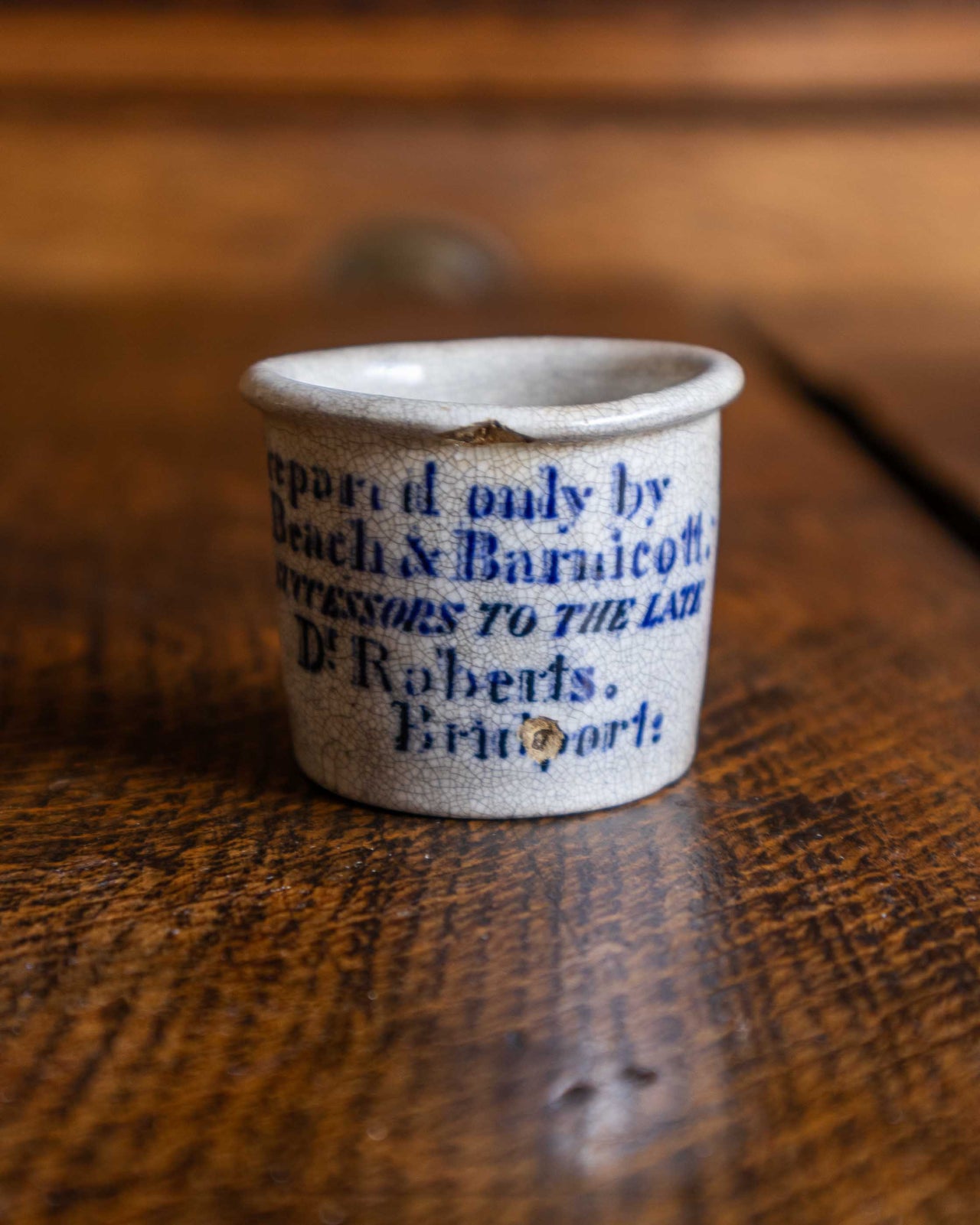 Small ceramic pot with blue text on a wooden surface