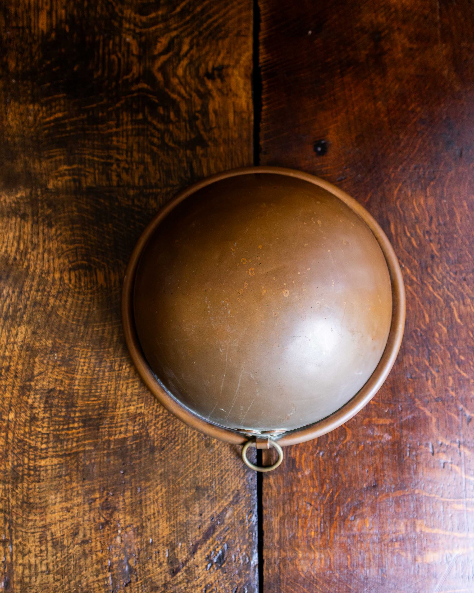 Copper bowl with handle on a wooden surface