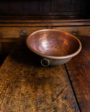 Copper bowl on a wooden surface with a dark background