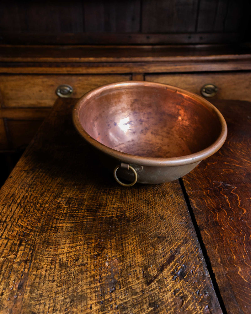 Copper bowl on a wooden surface with a dark background