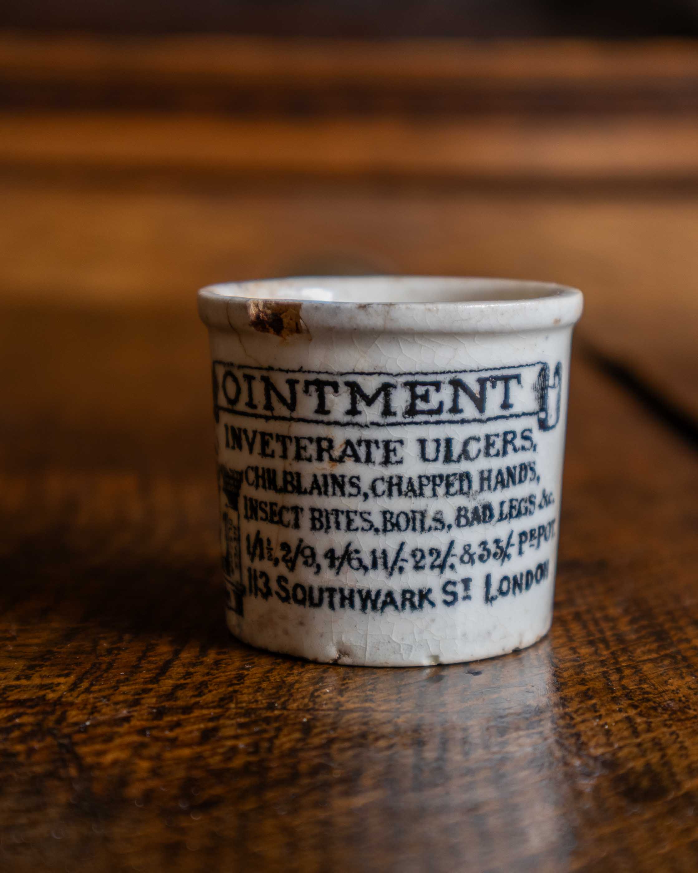 Small ceramic jar labeled 'Ointment' on a wooden surface