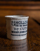 Small ceramic pot with text on a wooden surface