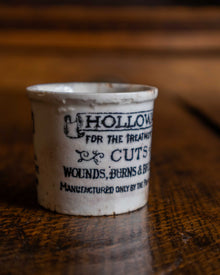 Small ceramic pot with text on a wooden surface