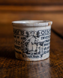Ceramic pot with text and illustration on a wooden surface