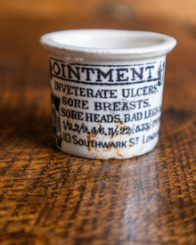 Vintage ceramic pot with text on a wooden surface