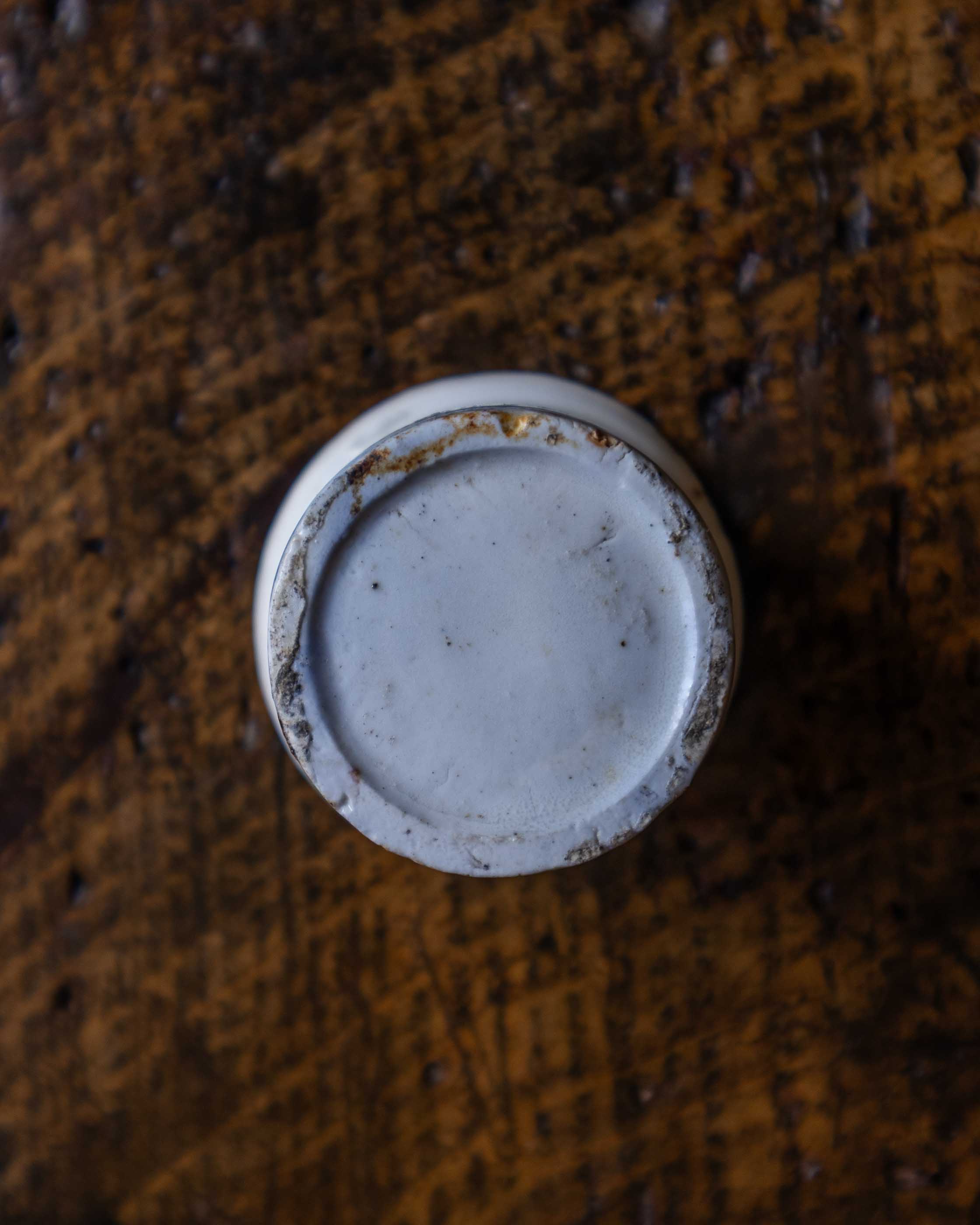 White ceramic pot on a brown textured surface