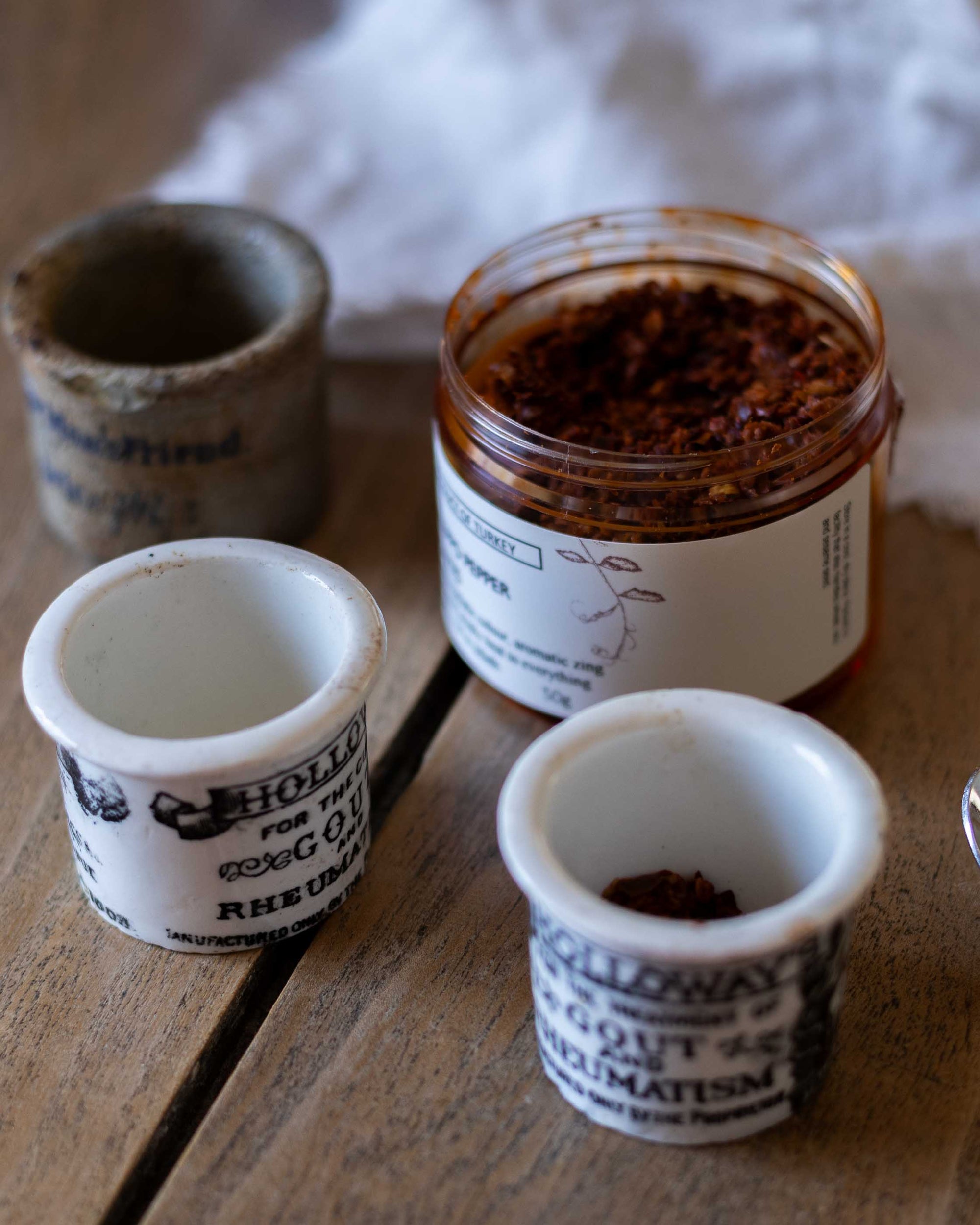 Three small pots on a wooden surface, containing  herbs and spices