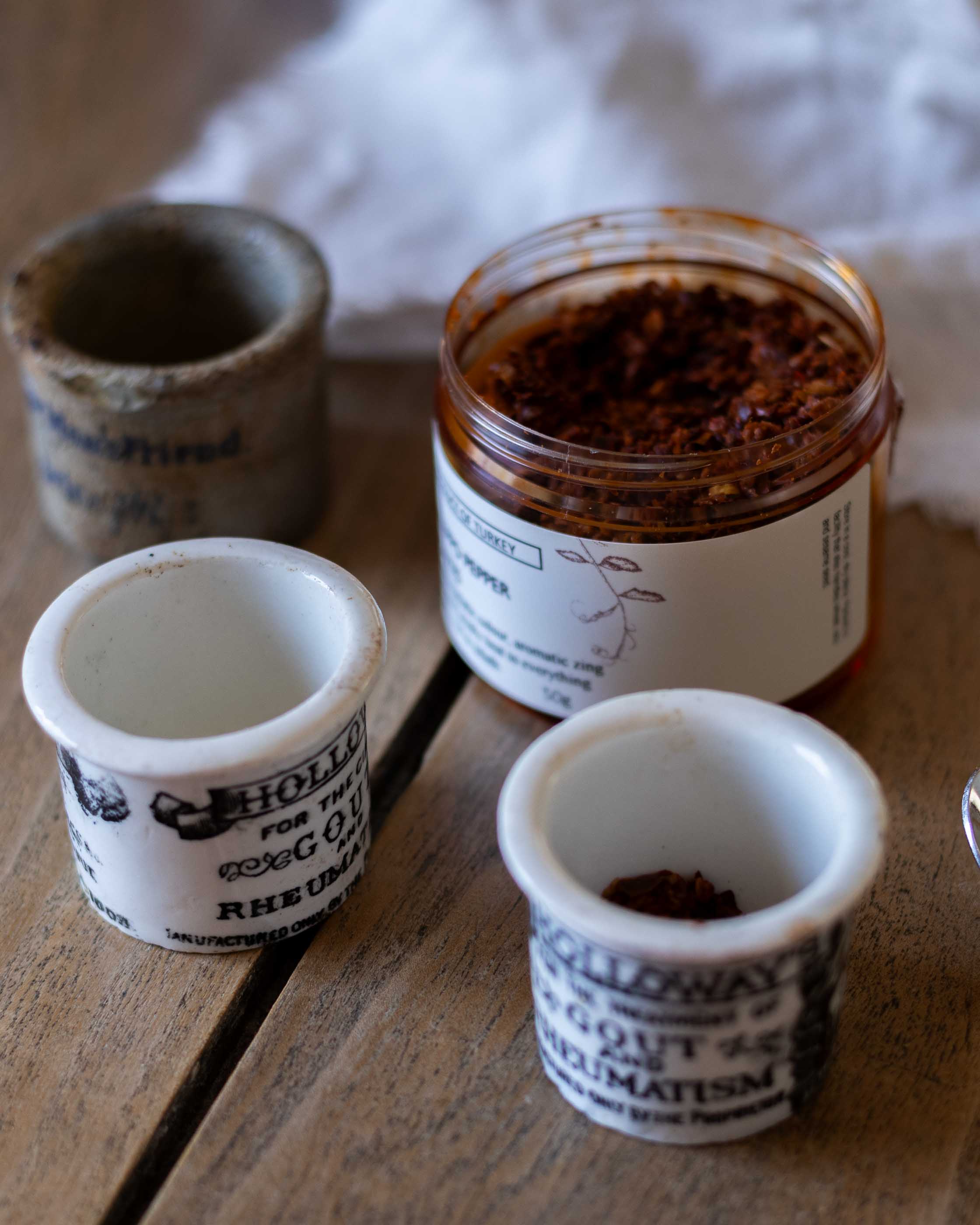 Three small pots on a wooden surface, containing  herbs and spices