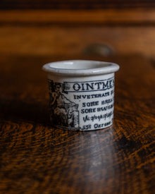 Ceramic pot with text and illustration on a wooden surface
