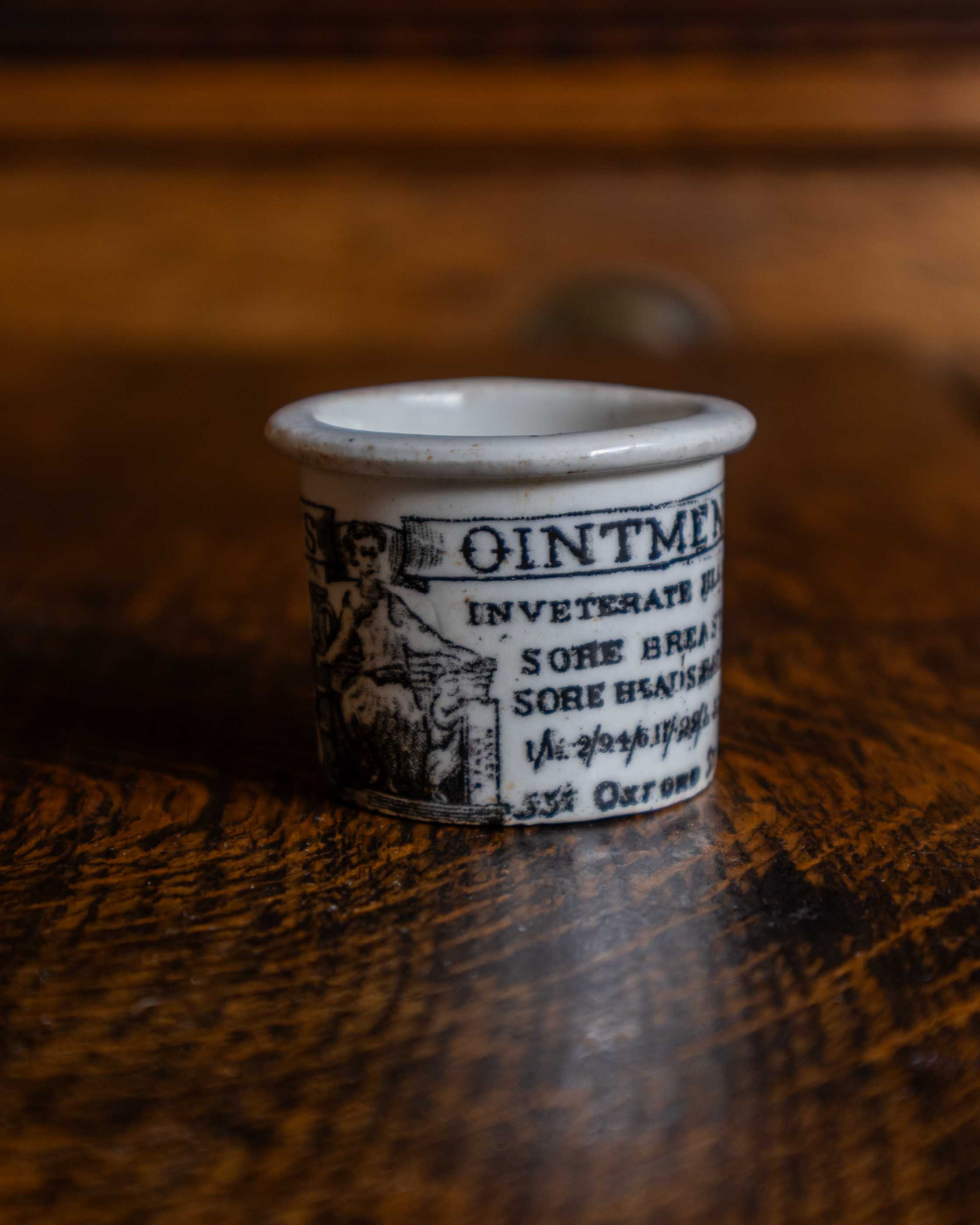 Ceramic pot with text and illustration on a wooden surface