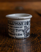 Ceramic pot with text and illustration on a wooden surface