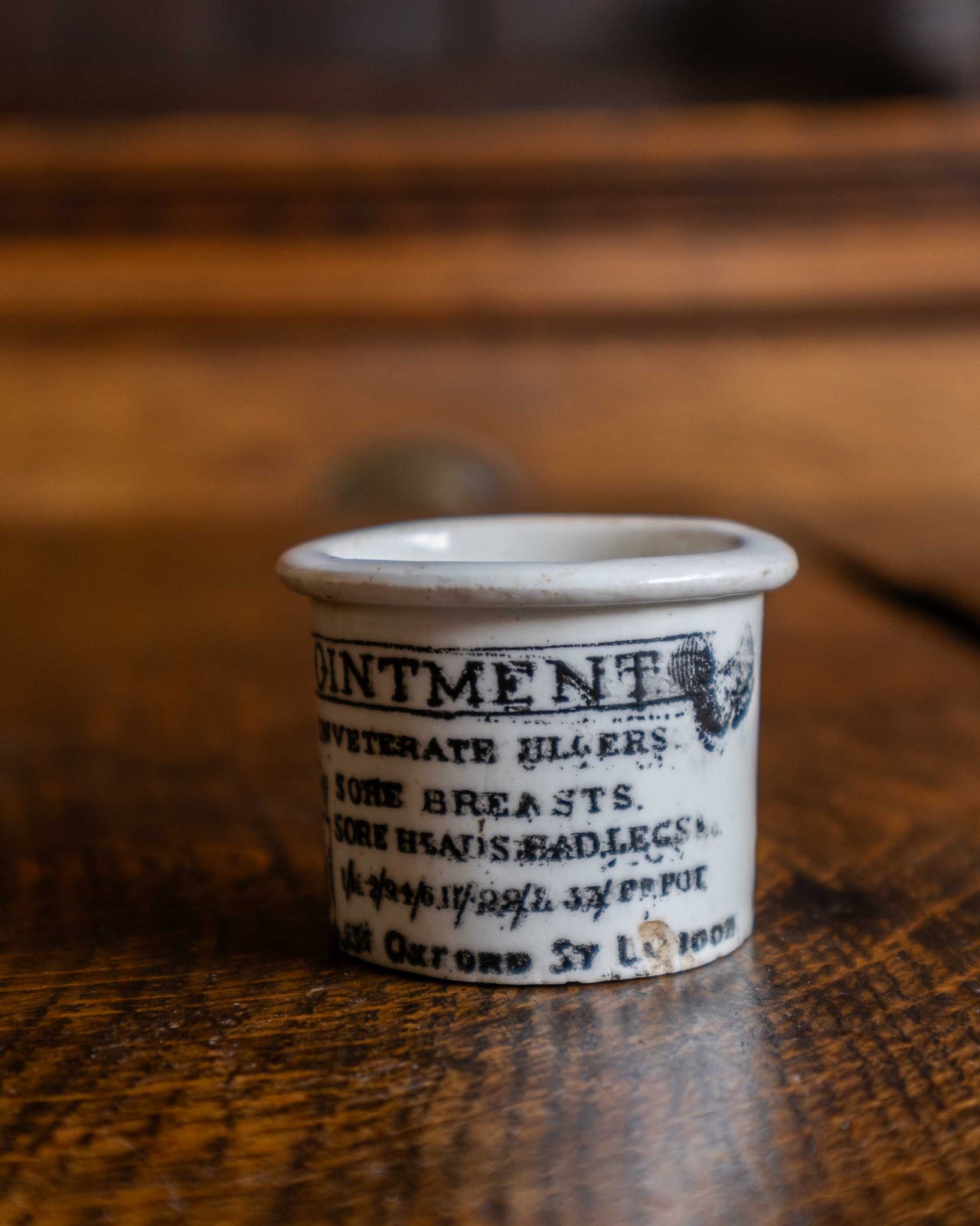 Ceramic pot with text and illustration on a wooden surface