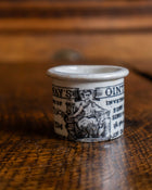 Ceramic pot with text and illustration on a wooden surface