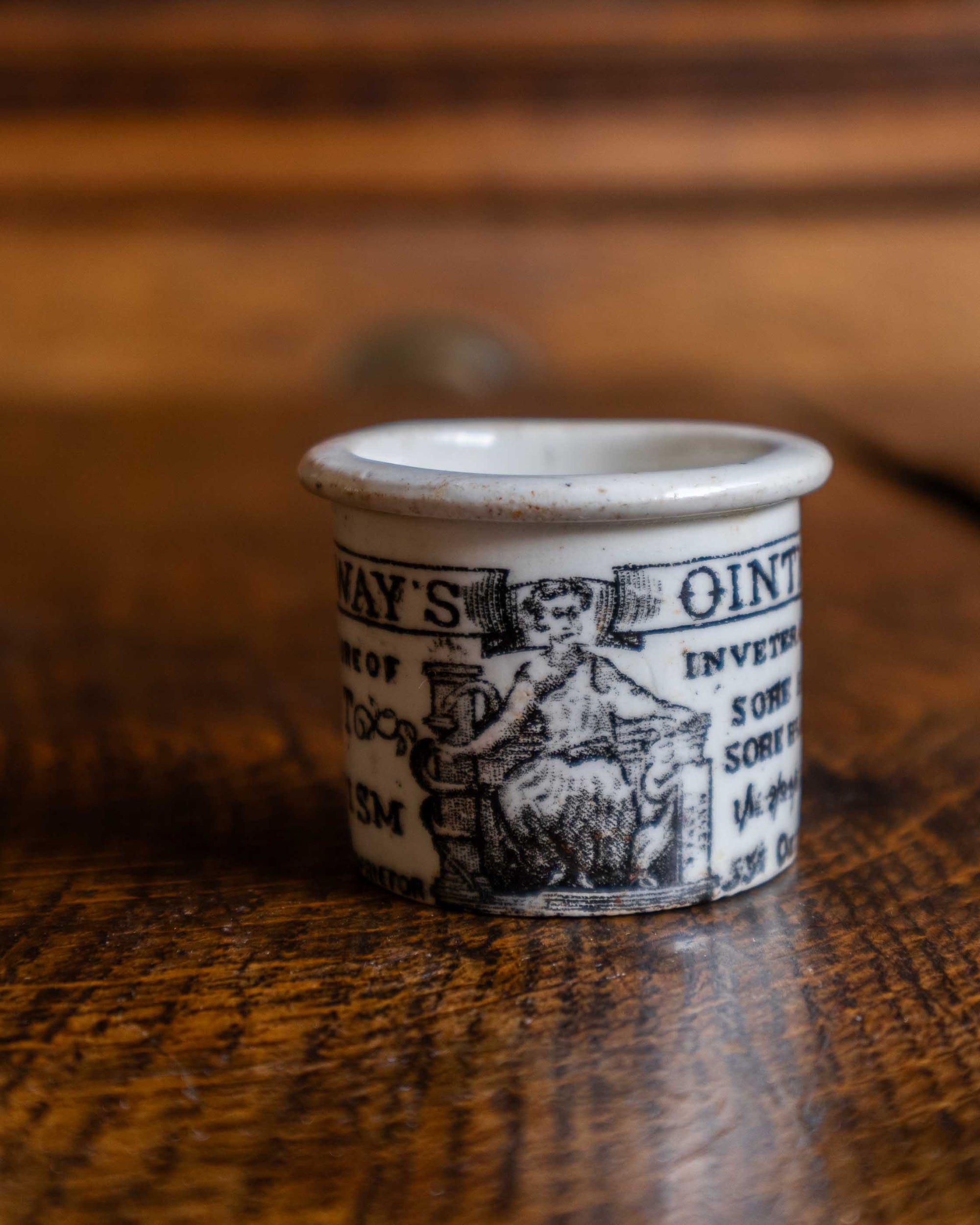 Ceramic pot with text and illustration on a wooden surface