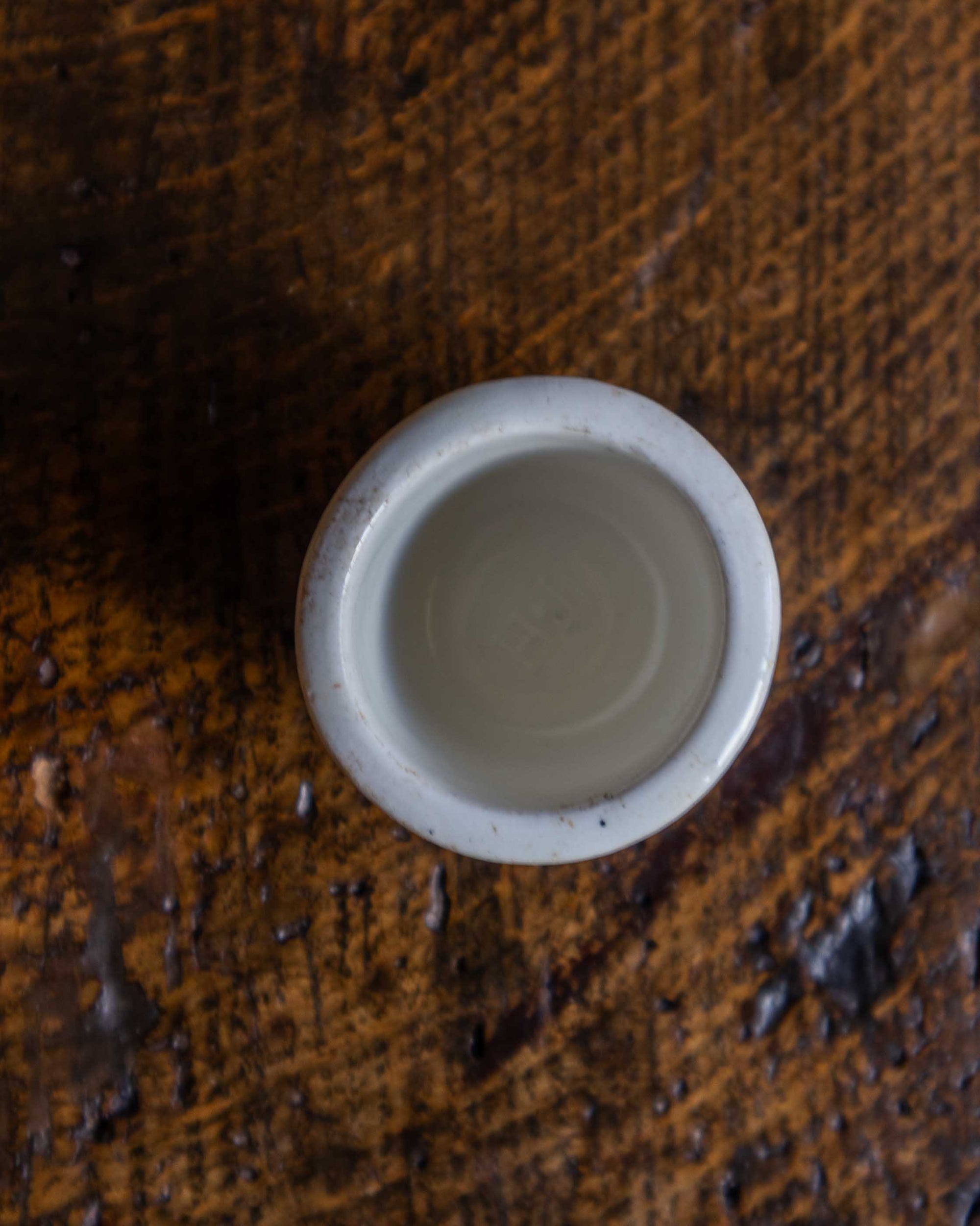 Small white ceramic pot on a textured brown surface
