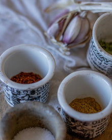Small ceramic pots with spices on a textured surface