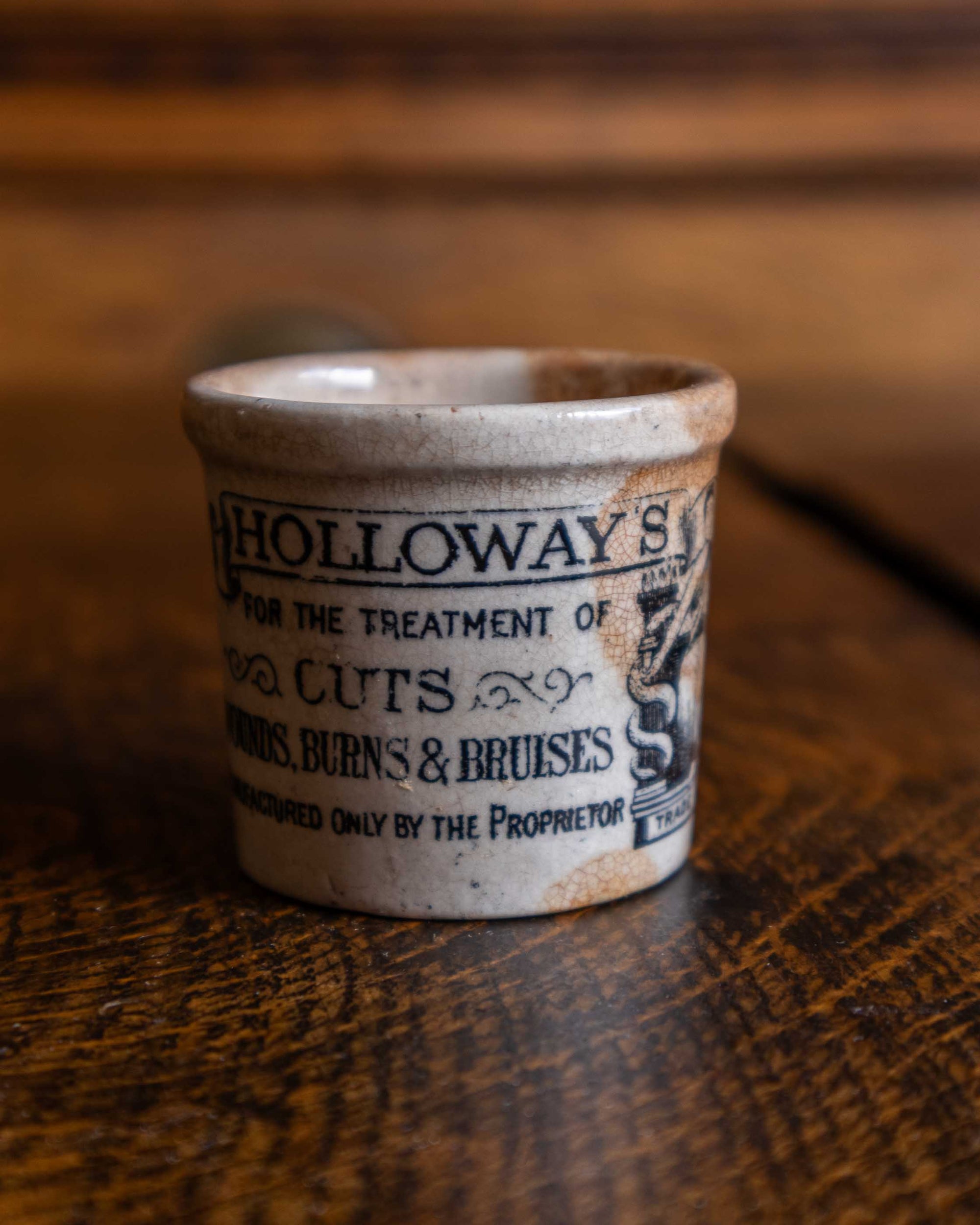 Vintage-style ceramic pot with text on a wooden surface