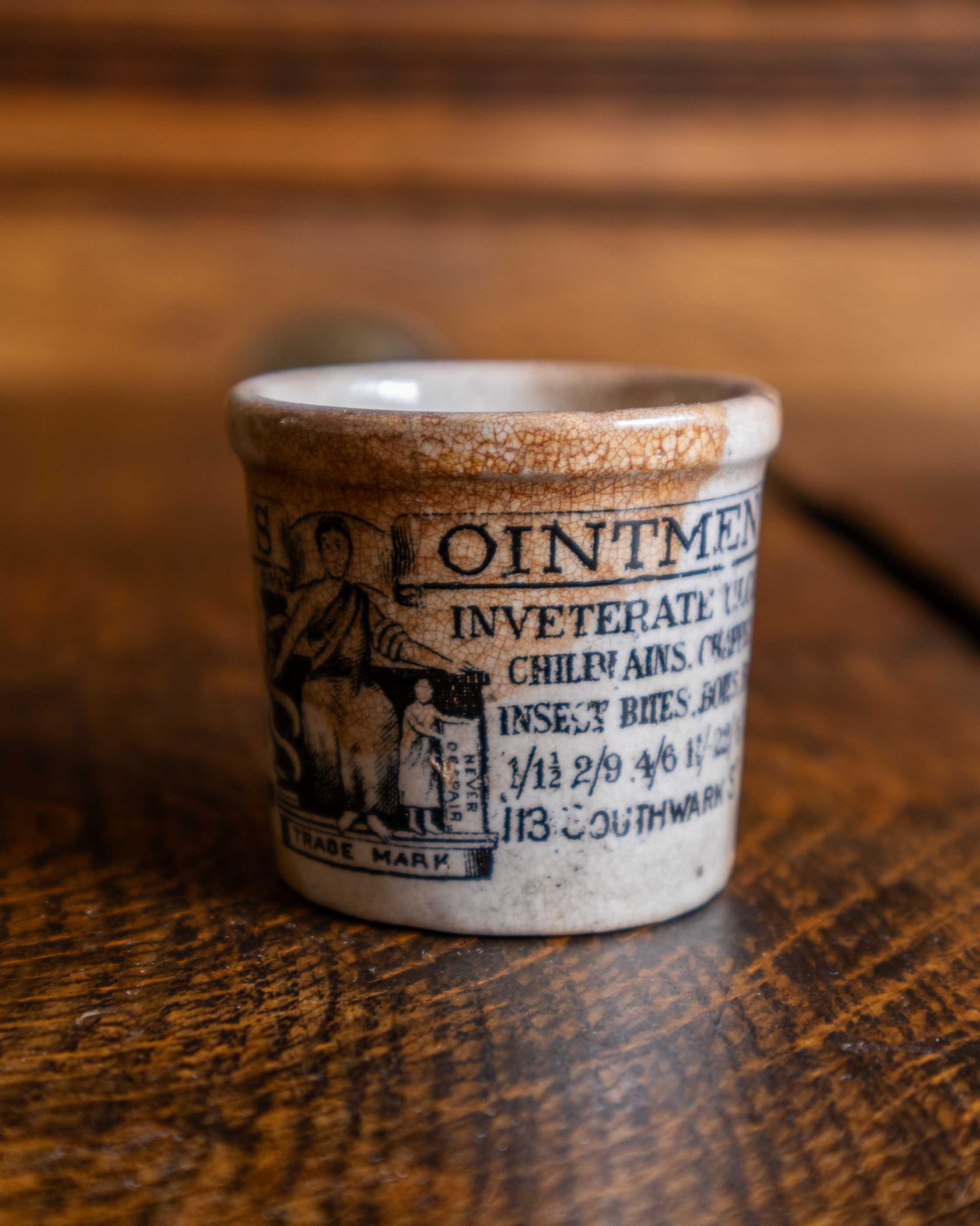Ceramic pot with text and illustration on a wooden surface