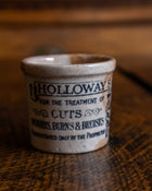 Ceramic pot with 'Holloway's' branding on a wooden surface