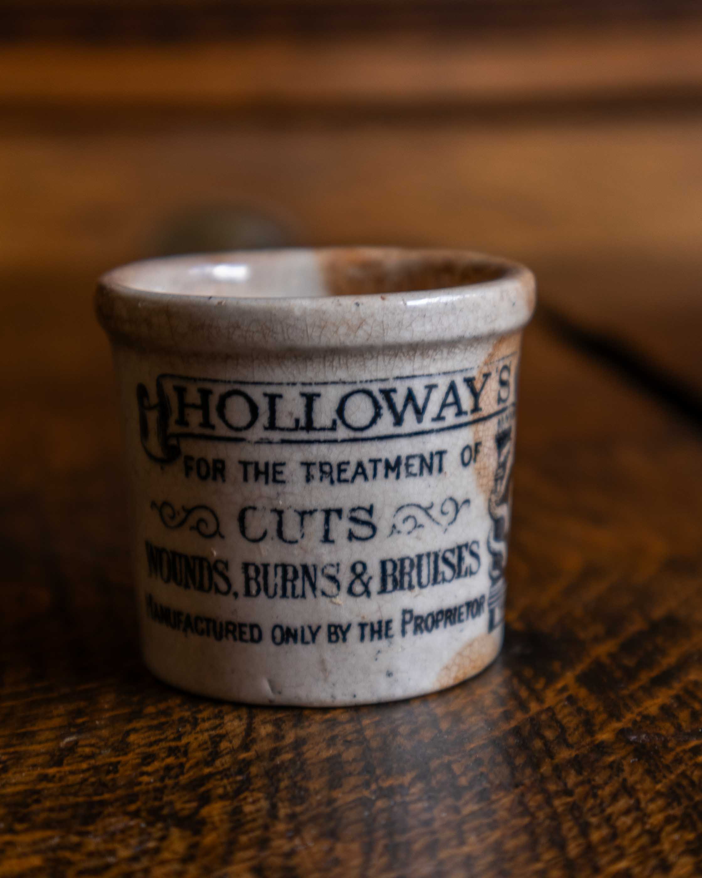 Ceramic pot with 'Holloway's' branding on a wooden surface