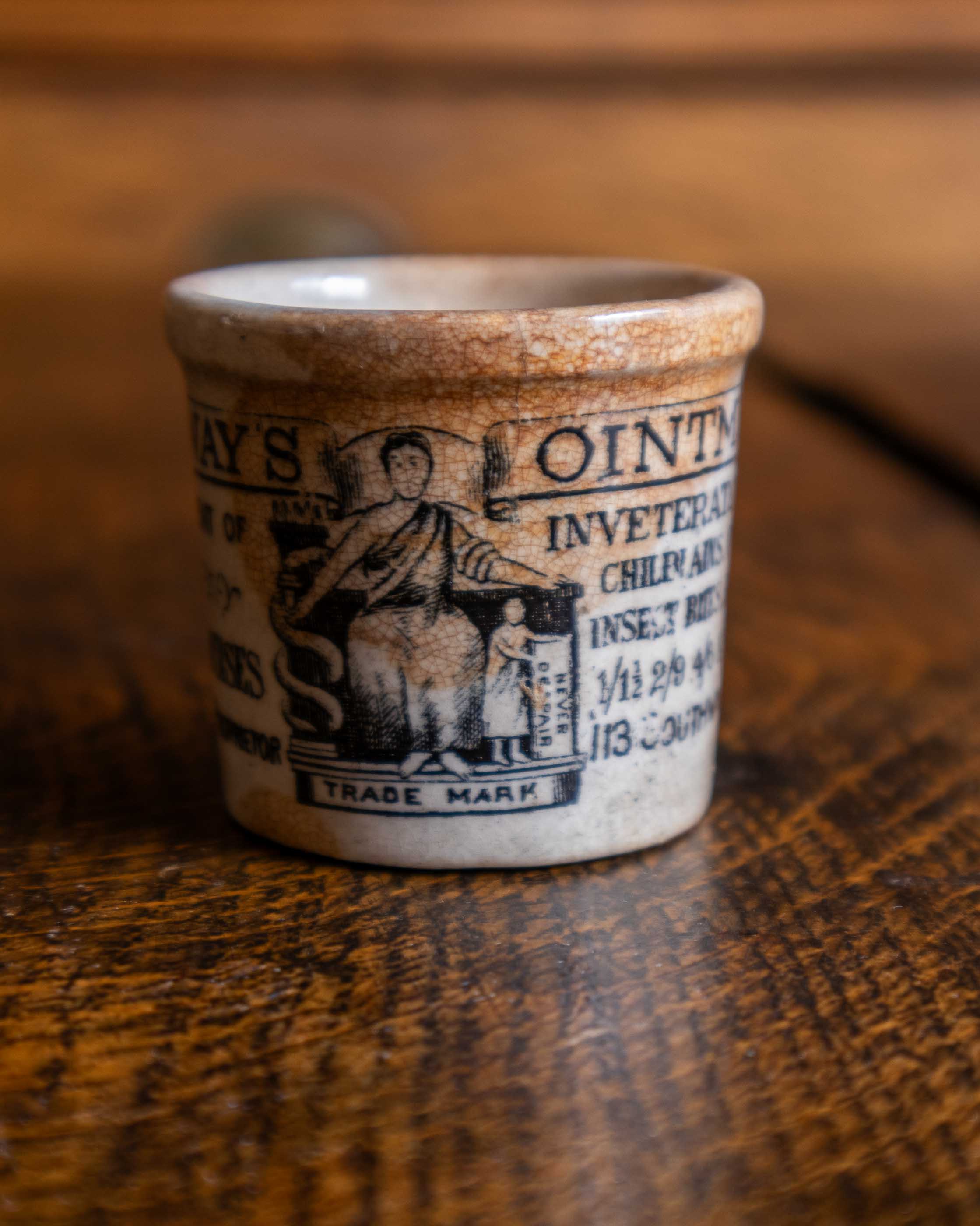 Ceramic pot with text and illustration on a wooden surface