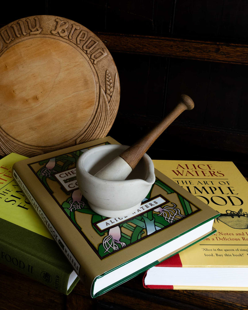 Mortar and pestle on a stack of cookbooks with a dark background