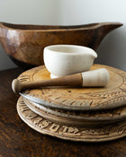 Mortar and pestle with a white bowl on a wooden surface