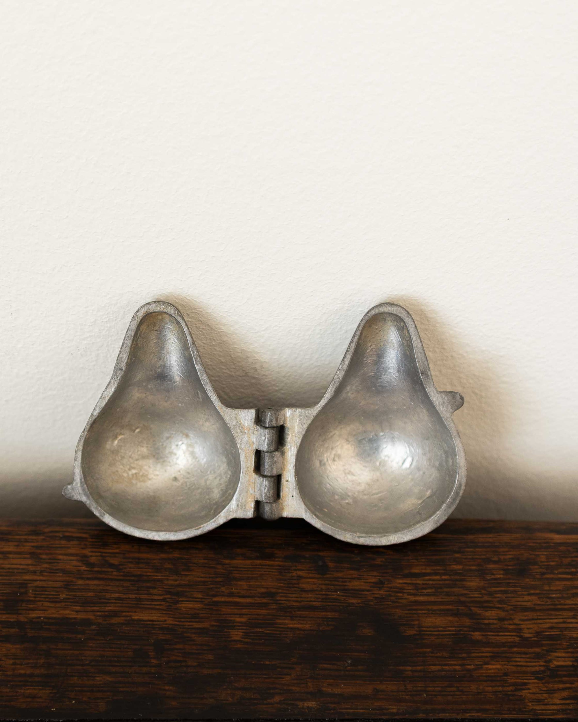 Pewter mould on a wooden surface with a white background