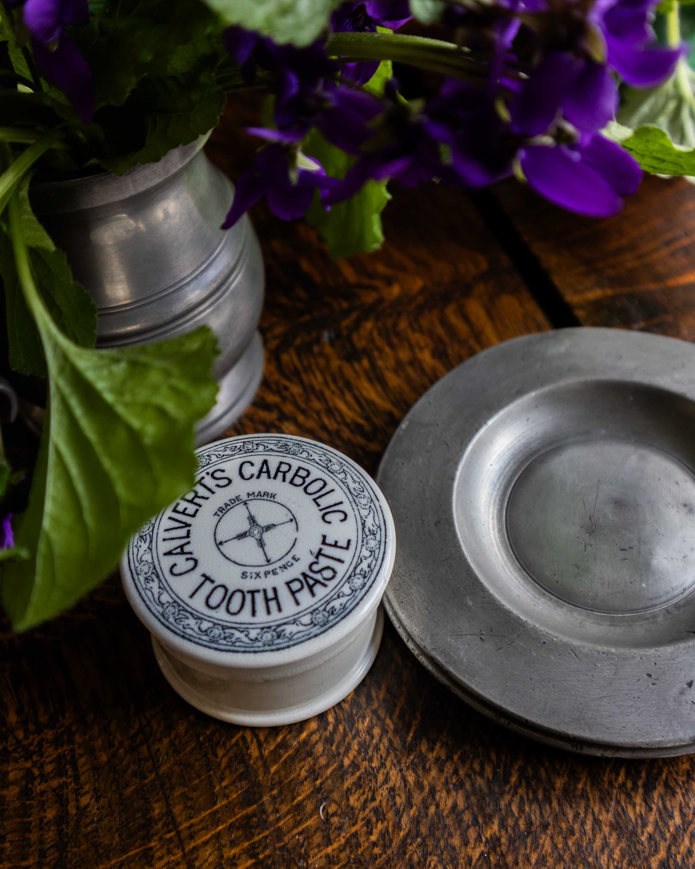 Calverts Carbolic Tooth Paste pot on a wooden surface with purple flowers.