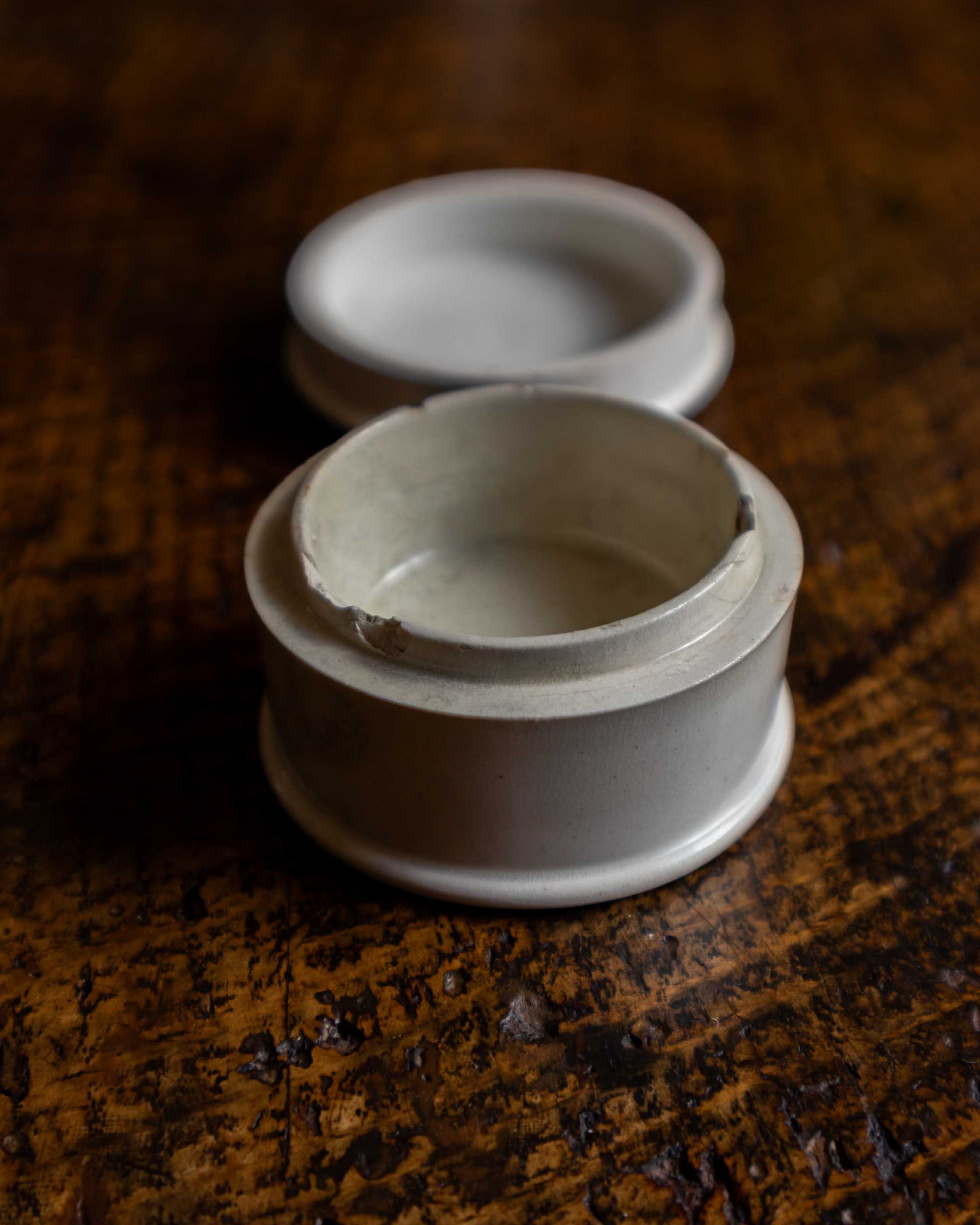 White ceramic container with a lid on a wooden surface