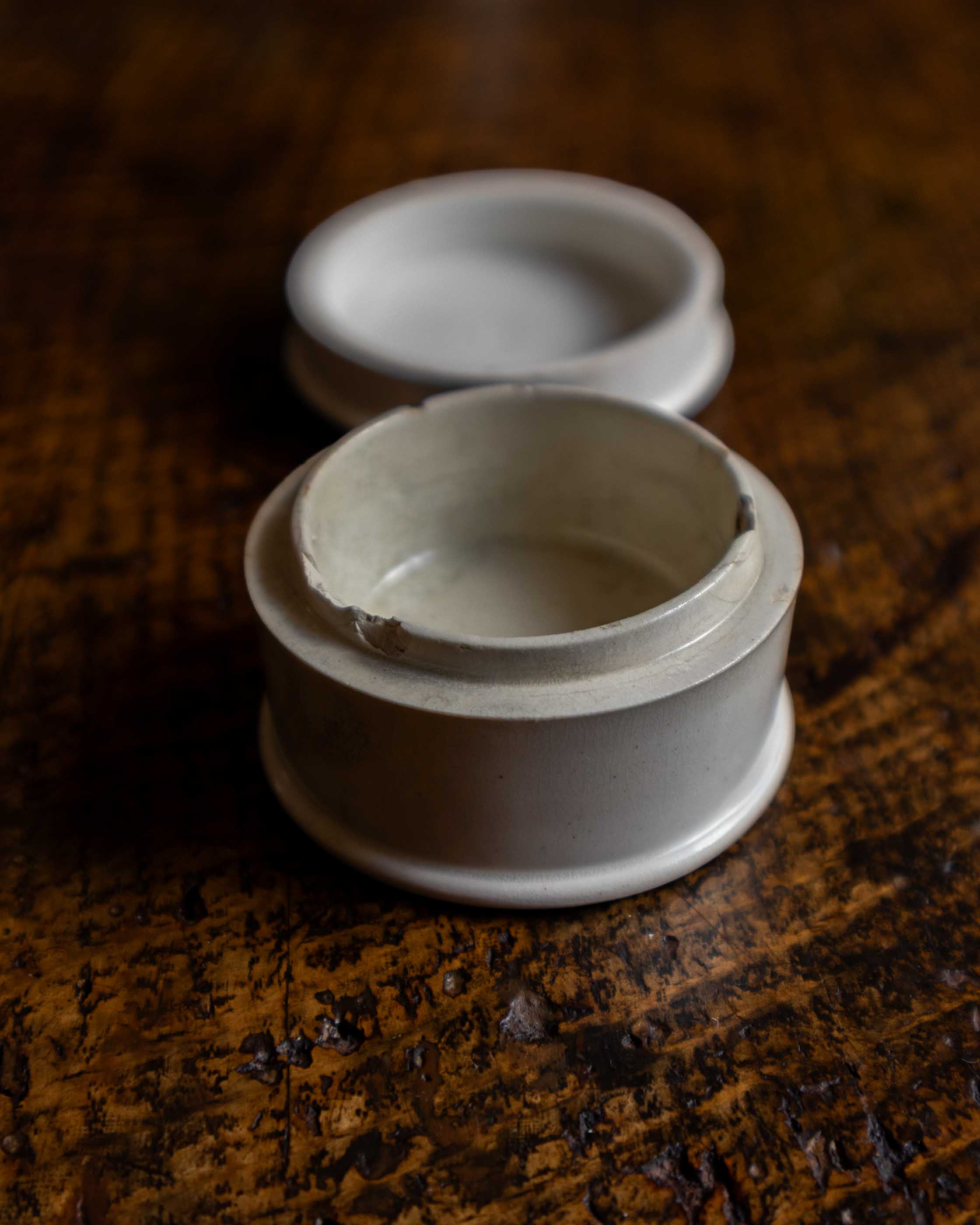 White ceramic container with a lid on a wooden surface