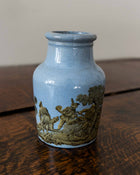 Blue ceramic jar with gold embossed design on a wooden surface