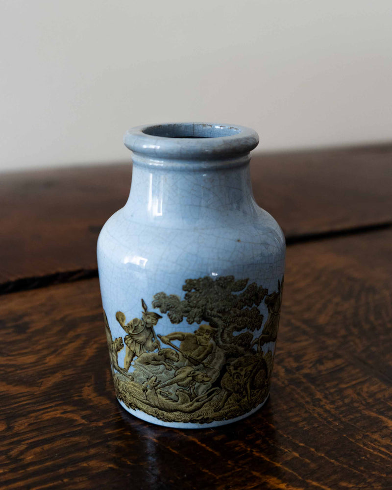 Blue ceramic jar with gold embossed design on a wooden surface