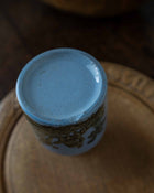 Ceramic jar with blue base on a wooden surface