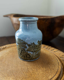 Blue ceramic jar with decorative patterns on a wooden surface