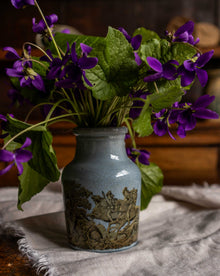 Prattware jar with purple flowers on a textured surface