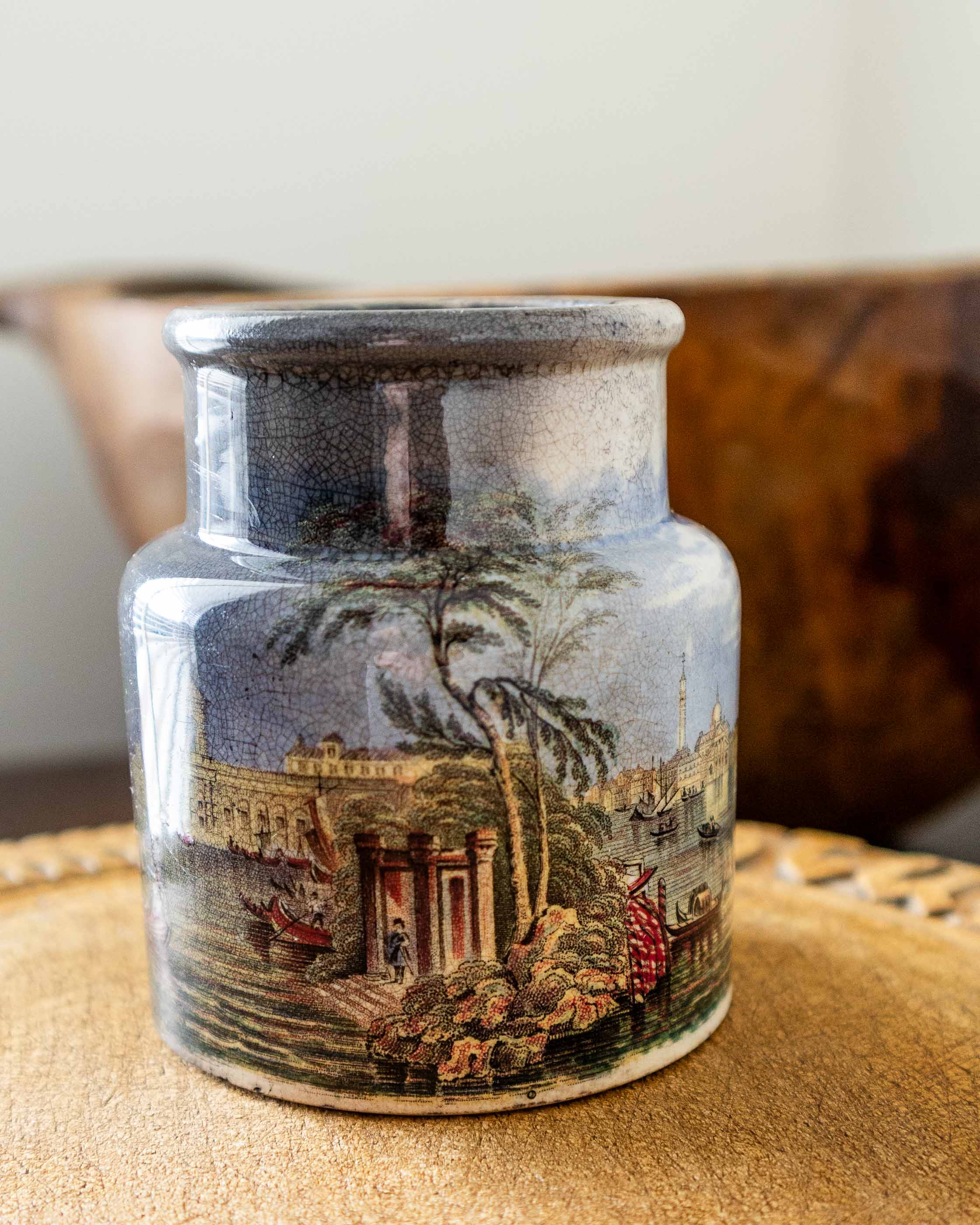 Decorative ceramic jar with scenic design on a wooden surface