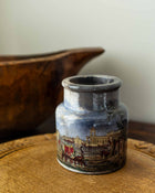 Decorative ceramic jar with a scenic design on a wooden surface