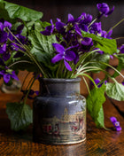 Purple flowers in a decorative prattware jar on a wooden surface
