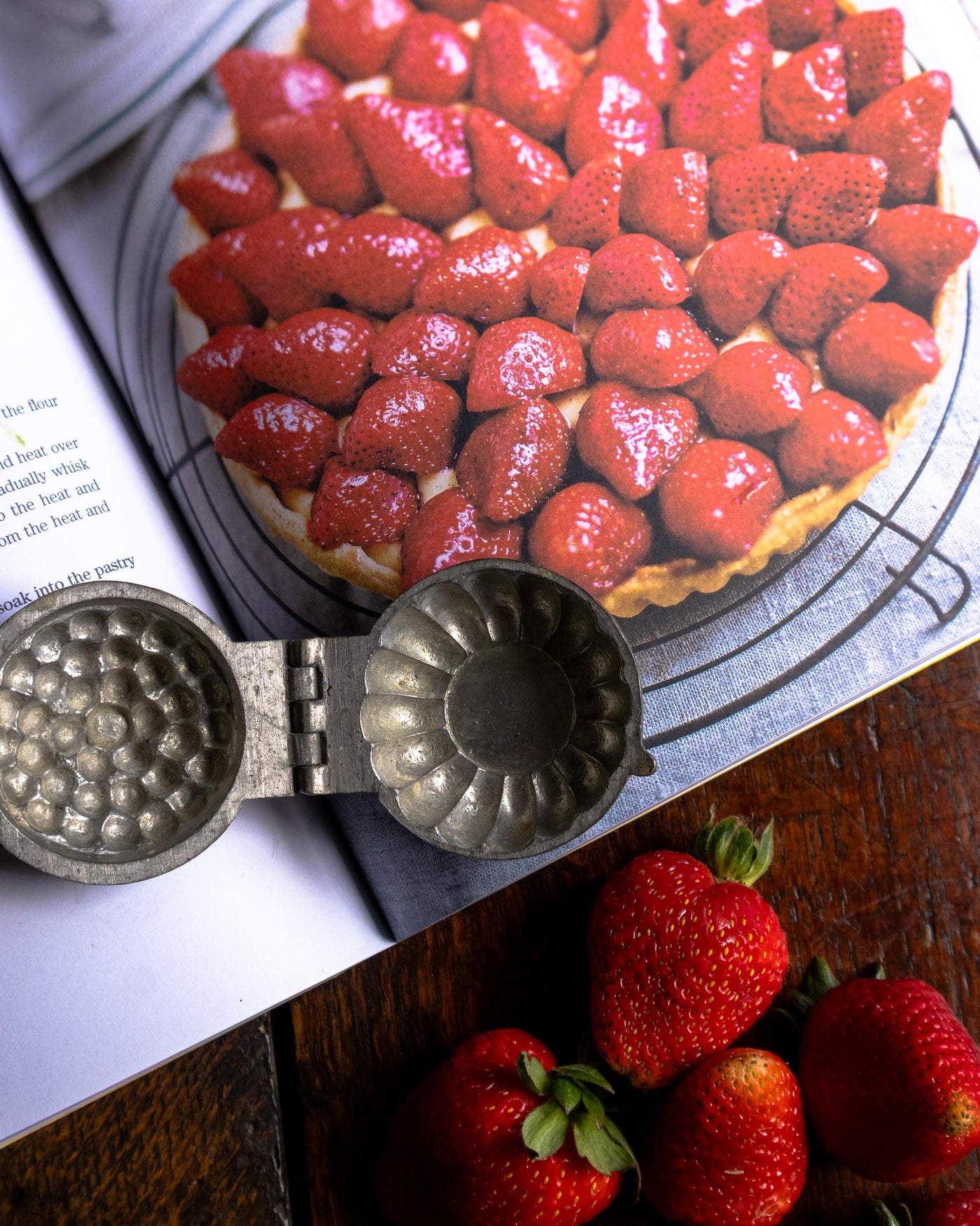 Strawberry tart with a pewter tartlet mould on a wooden surface