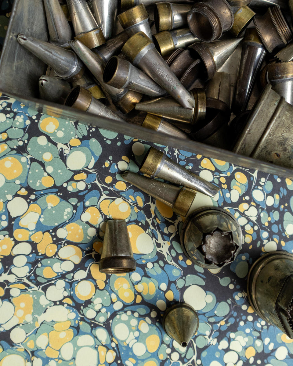 Collection of metal icing nozzles on a floral-patterned surface