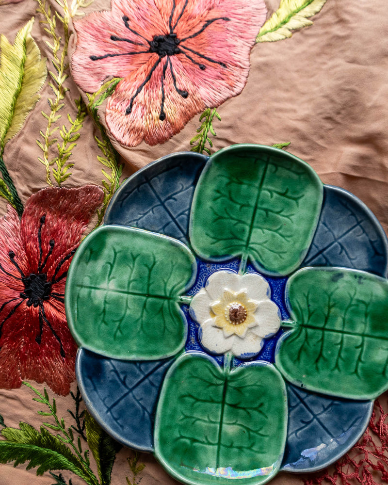 Antique majolica plate with floral design by Griffen, Smith & Hill on a textured fabric background