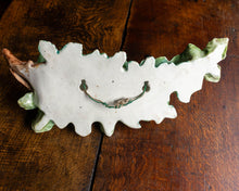 Decorative ceramic leaf-shaped object on a wooden surface