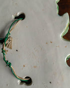Close-up of a green and beige cord on a ceramic surface